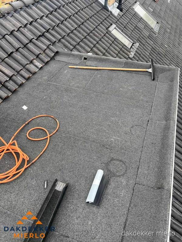 Plat dak reparatie met gereedschap en loodstroken in Mierlo