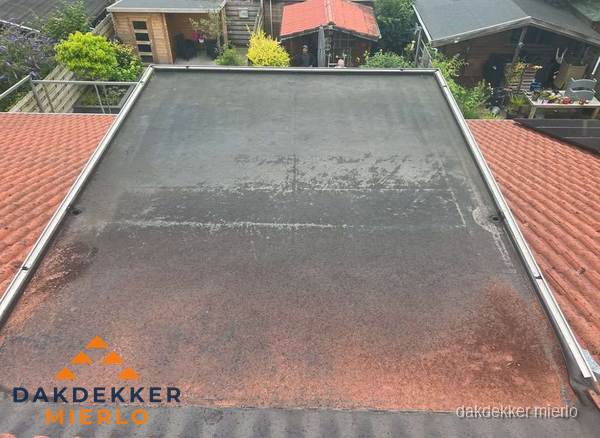 Verouderd plat dak met slijtage tussen schuine daken in Mierlo Verouderd plat dak met slijtage tussen schuine daken in Mierlo