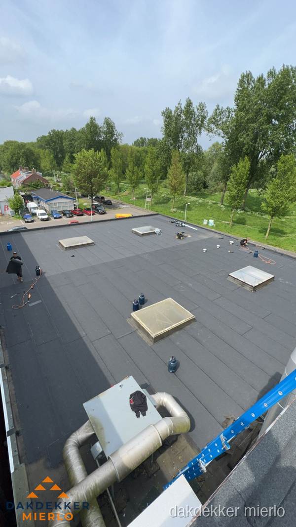 Dakdekker aan het werk op groot plat dak met bitumen in Mierlo