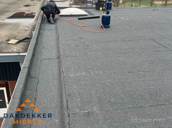 Dakdekker repareert bitumen dakbedekking op groot plat dak in Mierlo