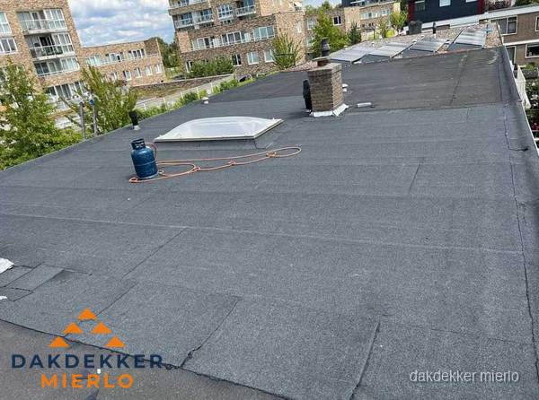 Bitumen dakbedekking op plat dak met lichtkoepel en schoorsteen in Mierlo